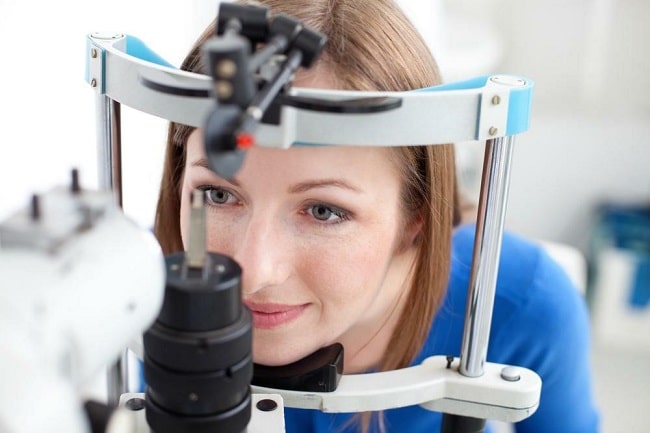 Woman undergoing eye exam, looking at camera.