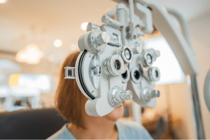 A woman examining her eyes using an eye exam machine.
