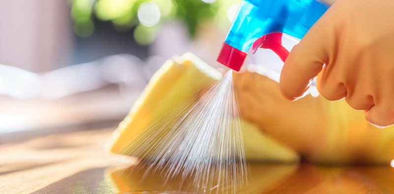 A person cleaning the table with spray